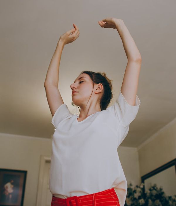 Woman in a comfortable athletic outfit stretching gently in a bright, minimalist room.